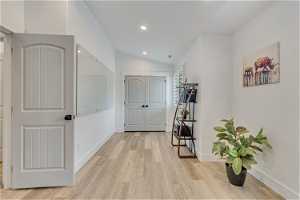 Hallway with light hardwood / wood-style floors and lofted ceiling