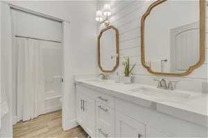 Full bathroom featuring hardwood / wood-style floors, shower / bath combo, toilet, and double vanity
