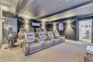 Carpeted home theater room with a textured ceiling and beam ceiling