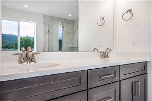 Bathroom with an enclosed shower, a mountain view, vanity with extensive cabinet space, and dual sinks