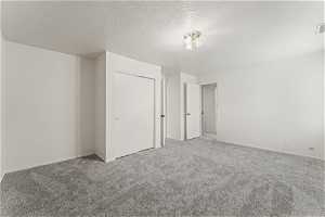 Unfurnished bedroom featuring a textured ceiling and carpet floors