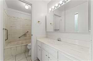Full bathroom featuring large vanity, toilet, enclosed tub / shower combo, and tile flooring
