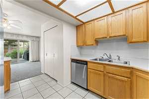 Kitchen with sink, ceiling fan, light tile floors, and stainless steel dishwasher
