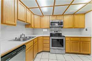 Kitchen with sink, stainless steel appliances, light tile flooring, and tasteful backsplash