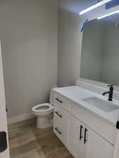 Half bathroom featuring wood-type flooring, toilet, and vanity