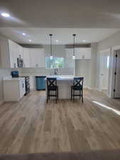 Kitchen with appliances with stainless steel finishes, white cabinets, and light hardwood / wood-style floors