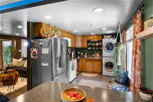 Kitchen featuring a wealth of natural light, stacked washing maching and dryer, white appliances, and sink