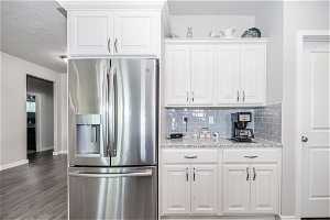 Kitchen featuring stainless steel fridge with ice dispenser, dark hardwood / wood-style flooring, tasteful backsplash, and white cabinetry