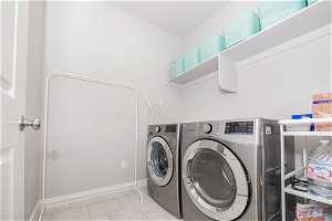 Clothes washing area with washing machine and dryer and light tile flooring