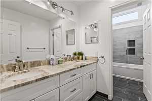 Bathroom featuring dual vanity, tiled shower / bath, and tile flooring