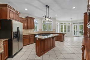 Kitchen featuring pendant lighting, light tile flooring, appliances with stainless steel finishes, sink, and a kitchen island