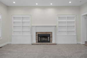 Unfurnished living room with carpet and a brick fireplace