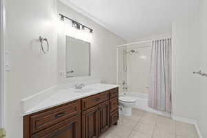 Full bathroom with toilet, shower / bath combo, tile floors, and vanity