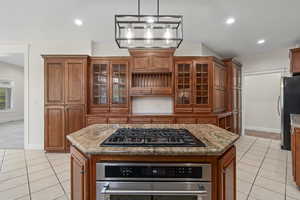 Kitchen with appliances with stainless steel finishes, a kitchen island, dark stone countertops, pendant lighting, and light tile floors