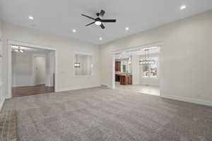 Interior space featuring ceiling fan with notable chandelier and light carpet