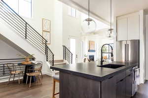 Kitchen featuring dark brown cabinetry, sink, decorative light fixtures, dark hardwood / wood-style flooring, and high quality fridge