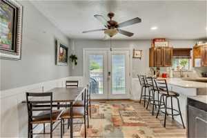 Dining room featuring french doors, light hardwood / wood-style flooring, ceiling fan, and a textured ceiling
