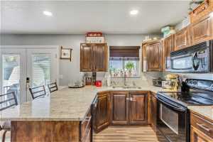 Kitchen featuring sink, light hardwood / wood-style flooring, black appliances, and plenty of natural light