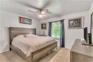 Bedroom featuring carpet flooring, ceiling fan, and a textured ceiling