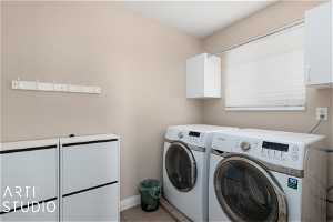 Laundry room with washer and clothes dryer, tile floors, and cabinets