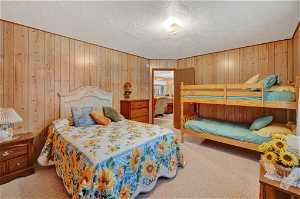 Bedroom with wooden walls, carpet flooring, and a textured ceiling