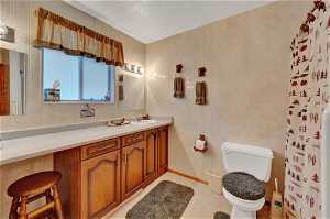 Bathroom with vanity, tile walls, tasteful backsplash, toilet, and a textured ceiling
