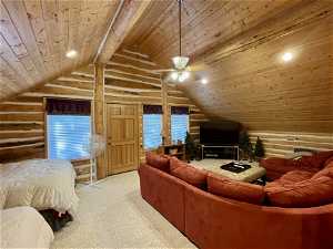 Carpeted bedroom/media room  featuring wood ceiling, multiple windows, rustic walls, and lofted ceiling
