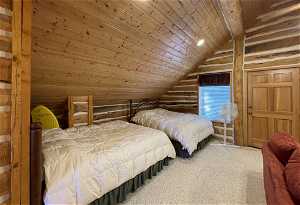 Bedroom/media room  featuring wooden ceiling, lofted ceiling, rustic walls, and carpet flooring