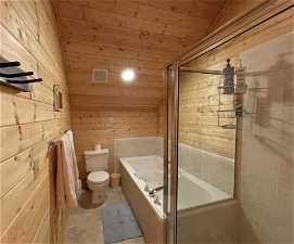 Bathroom with wood walls, tile flooring, wood ceiling, toilet, and lofted ceiling