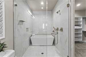 Bathroom featuring tile walls, tile floors, toilet, and separate shower and tub