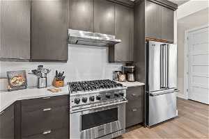 Kitchen featuring appliances with stainless steel finishes, dark brown cabinetry, and light wood-type flooring