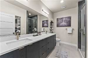 Bathroom with double sink, a shower with door, tile flooring, and large vanity