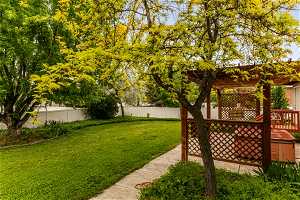 View of secluded yard with a pergola and a wooden deck