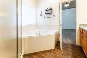 Bathroom with wood-type flooring, vanity, and a soaking tub