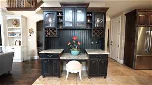 Kitchen area with high end refrigerator, light tile floors, and dark brown cabinetry and desk