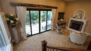 Carpeted living room featuring a fireplace with sliding glass door to side yard next to waterfall
