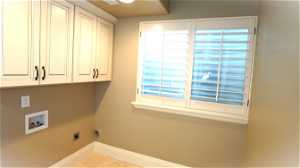 Basement Laundry room with washer hookup, hookup for an electric dryer, cabinets, and light tile floors