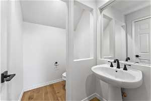 Half bathroom featuring hardwood / wood-style floors, Pedestal sink.