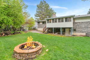 Back of property featuring 2 central AC units, an outdoor fire pit, and a luscious lawn