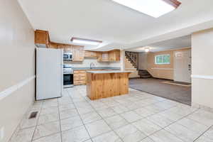 ADU: Kitchen featuring white refrigerator, a kitchen island, electric range, light tile floors and new paint