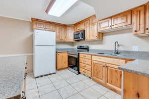 ADU: Kitchen featuring appliances with stainless steel finishes, a textured ceiling, sink, and light tile floors