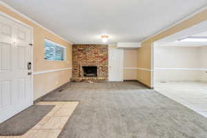 ADU: Large living room with ornamental molding, a textured ceiling, a brick fireplace, and light tile floors