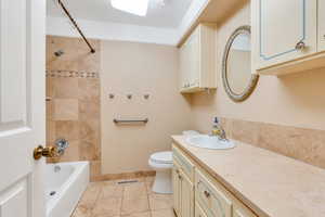 Full Bath featuring tiled shower / bath combo, vanity, tile floors, and toilet