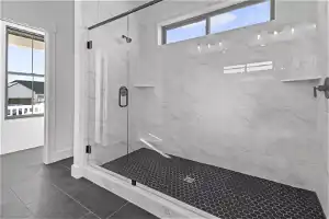 Bathroom featuring tile flooring and a shower with shower door