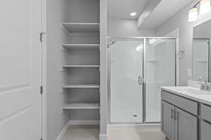 Bathroom with vanity with extensive cabinet space, an enclosed shower, and tile floors