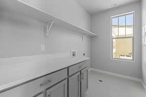 Laundry area featuring plenty of natural light, hookup for a washing machine, hookup for an electric dryer, and light tile flooring