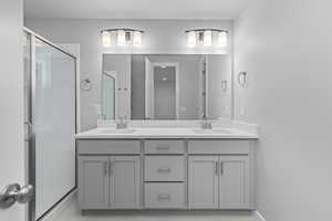 Bathroom featuring a shower with door, oversized vanity, and double sink