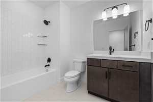 Full bathroom with tile floors, tiled shower / bath combo, oversized vanity, and toilet