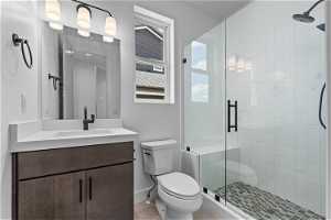 Bathroom with vanity with extensive cabinet space, an enclosed shower, toilet, and tile floors