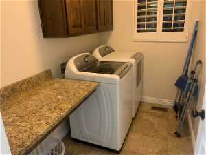 Clothes washing area with cabinets, independent washer and dryer, tile floors, and hookup for a washing machine